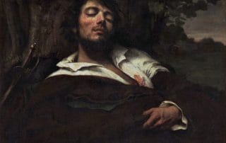 Un homme allongé, torse nu, dans une pose mélancolique et théâtrale, les yeux clos, représentant une beauté virile empreinte de douleur et de contemplation.